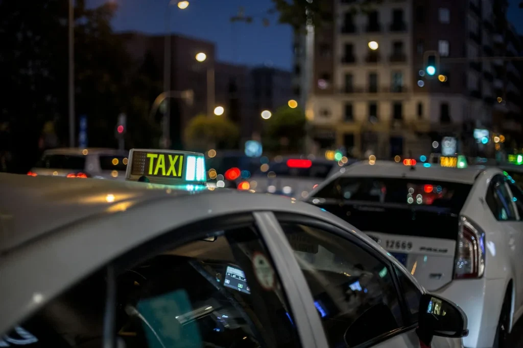 Taxi vehicles waiting for passengers on a street in downtown Reykjavik at night.