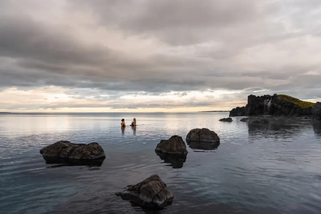 Visitors relaxing in the warm waters of Sky Lagoon overlooking Iceland's coastline.